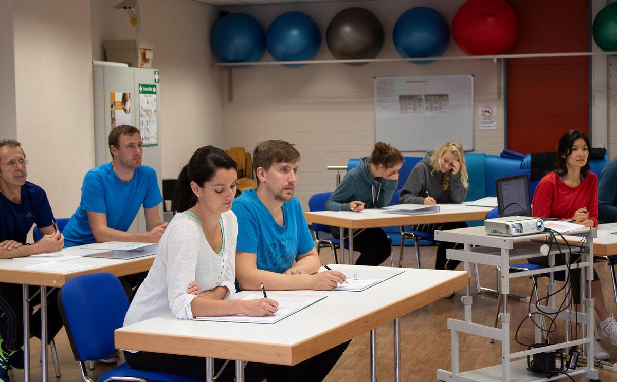 Teilnehmende sitzen im Unterrichtsraum und machen sich Notizen