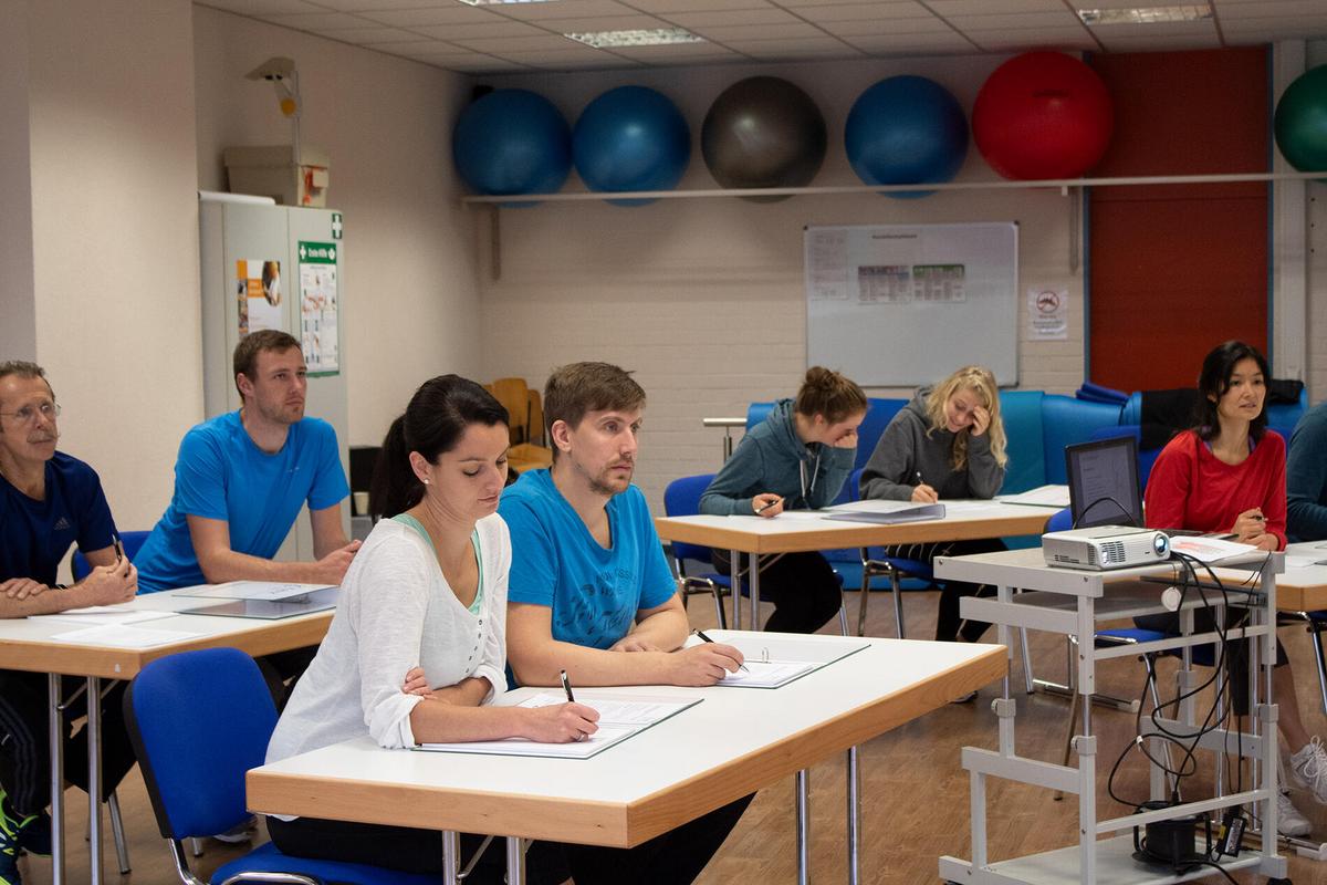Teilnehmende sitzen im Unterrichtsraum und machen sich Notizen