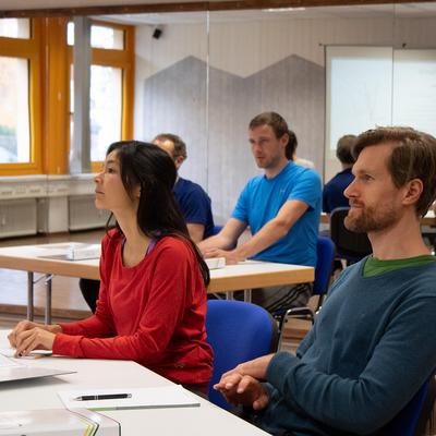 Teilnehmende sitzen im Seminarraum und folgen einer Präsentation