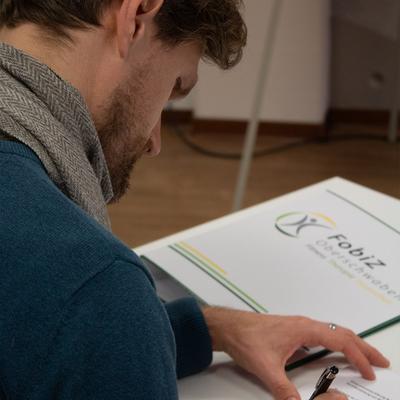 Teilnehmer schreibt Notizen in einen FobiZ-Ordner.